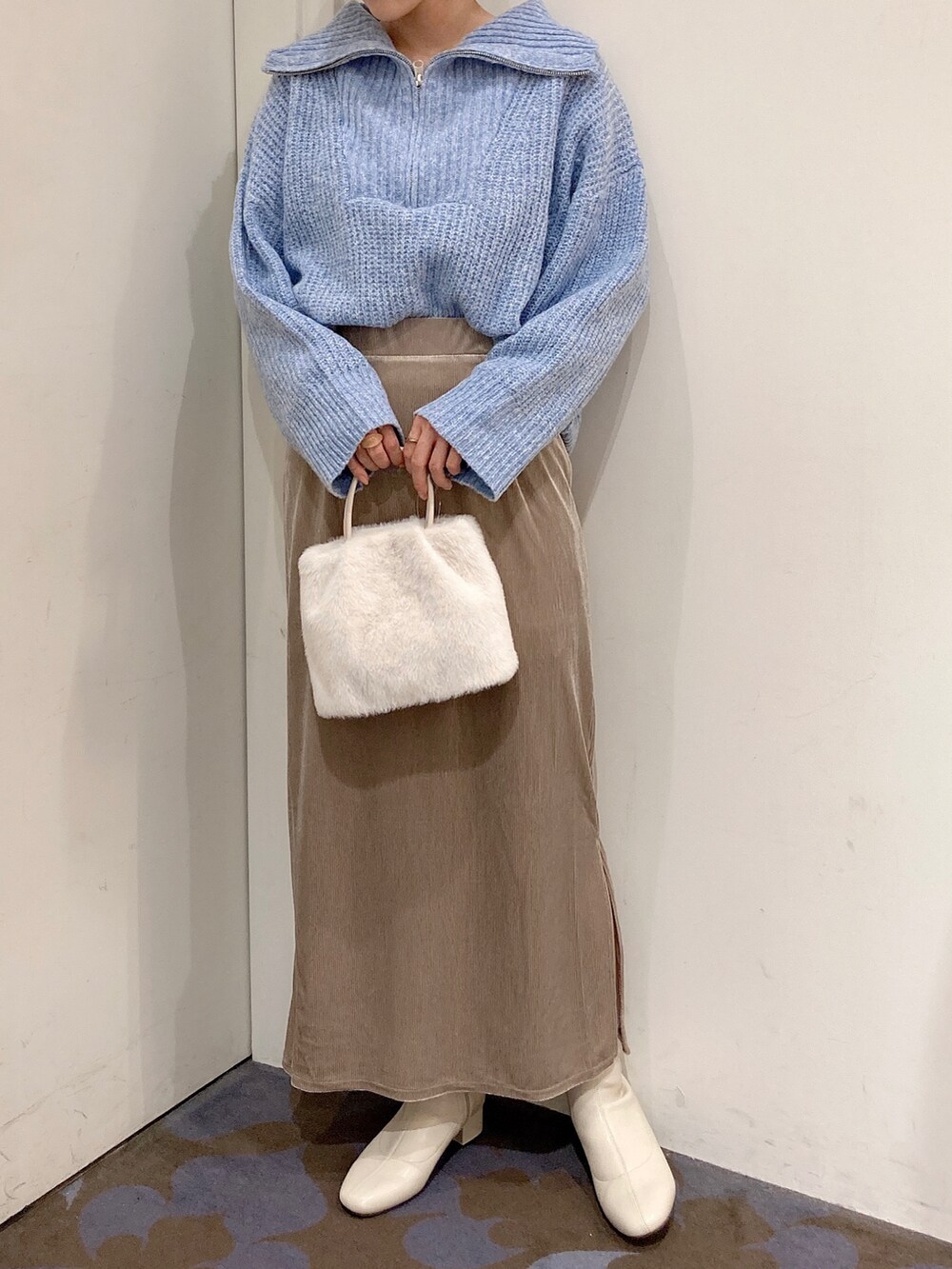 ベージュ系のスカート、ホワイト系のトートバッグ、ホワイト系のブーツを着用したレディースの秋コーディネートの2枚目の写真