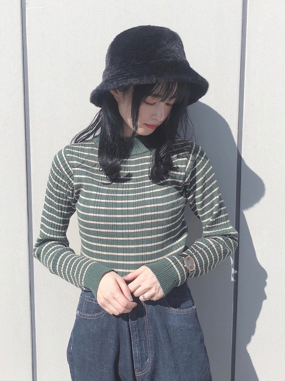 グリーン系のニット/セーター、ブルー系のデニムパンツ、ブラック系のショルダーバッグを着用したレディースの秋コーディネートの2枚目の写真