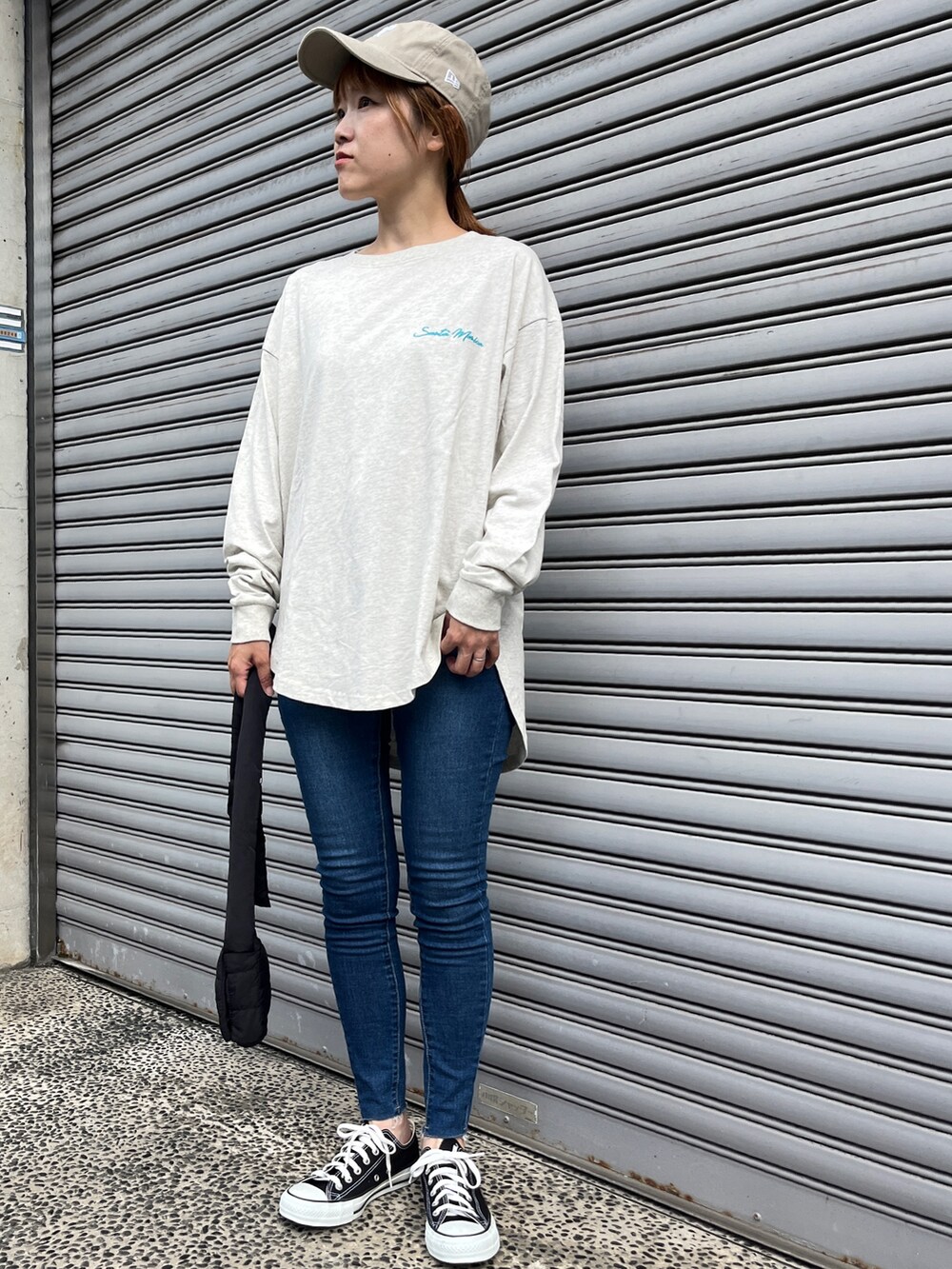 ホワイト系のTシャツ/カットソー、ブルー系のデニムパンツ、ブラック系のスニーカーを着用したレディースの秋コーディネートの2枚目の写真