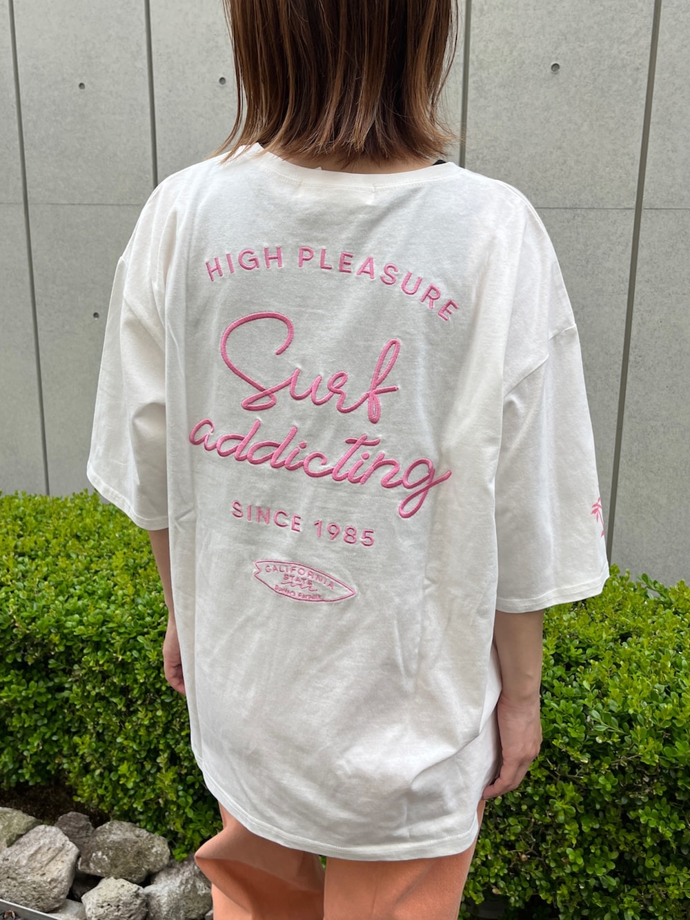 ホワイト系のTシャツ/カットソー、オレンジ系のデニムパンツ、ベージュ系のトートバッグを着用したレディースの春コーディネートの3枚目の写真