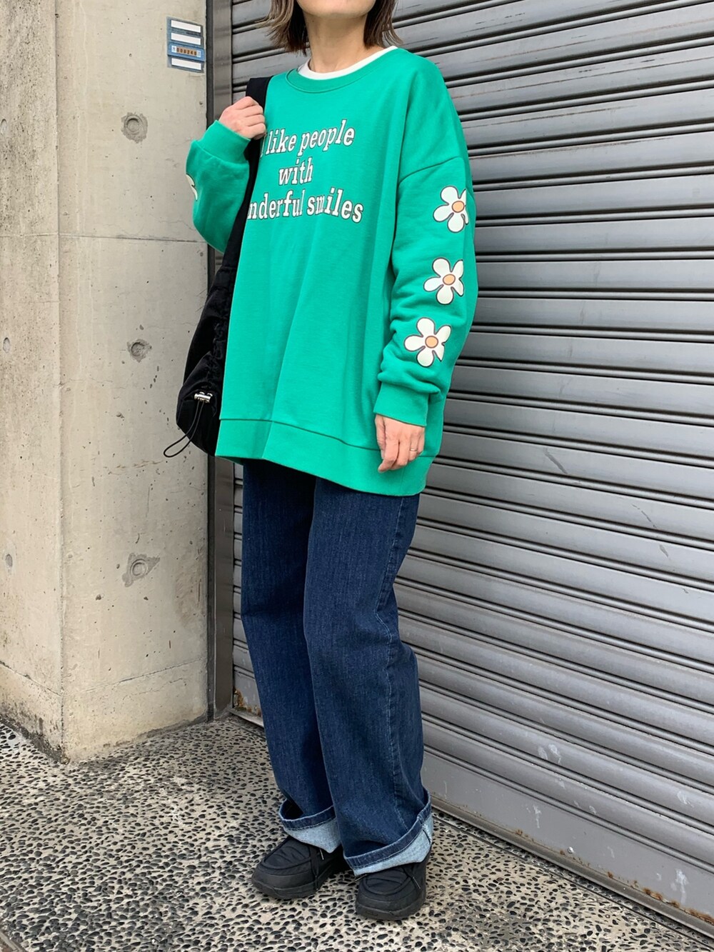 グリーン系のスウェット、ブルー系のデニムパンツ、ブラック系のシューズを着用したレディースの冬コーディネートの2枚目の写真