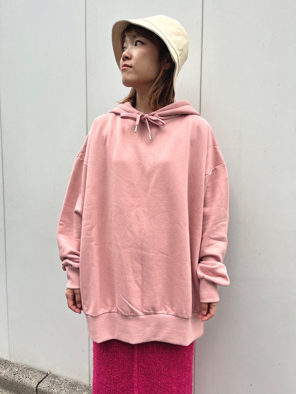 ピンク系のパーカー、ピンク系のスカート、ホワイト系のショルダーバッグを着用したレディースの秋コーディネートの2枚目の写真