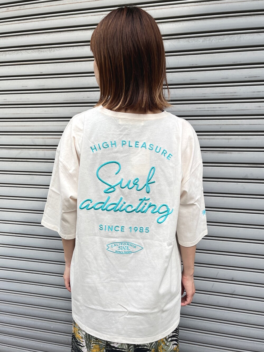 ベージュ系のTシャツ/カットソー、ベージュ系のトートバッグ、グリーン系のスカートを着用したレディースの春コーディネートの4枚目の写真