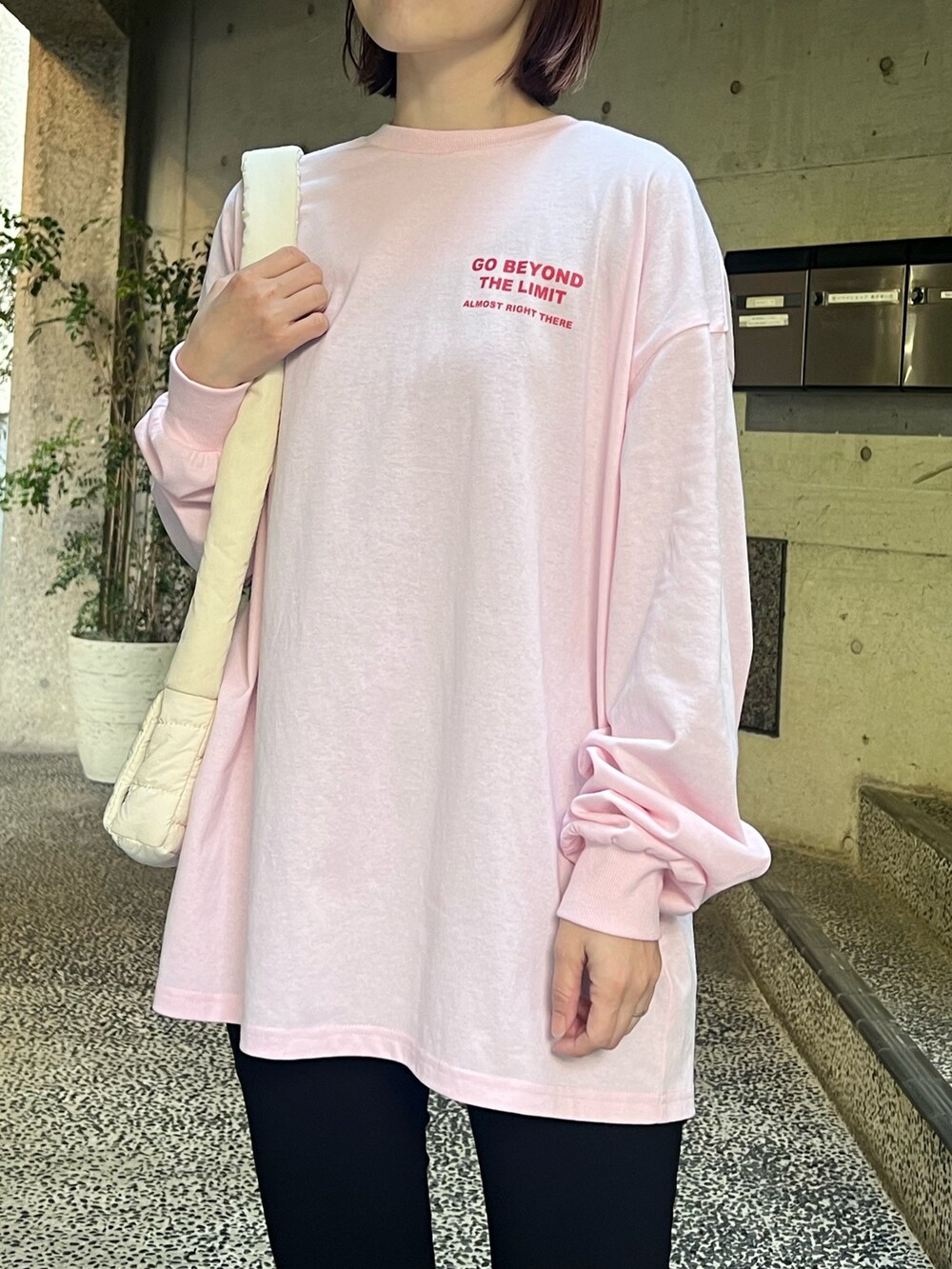 ピンク系のTシャツ/カットソー、ホワイト系のショルダーバッグ、ブラック系のレギンス/スパッツを着用したレディースの春コーディネートの2枚目の写真