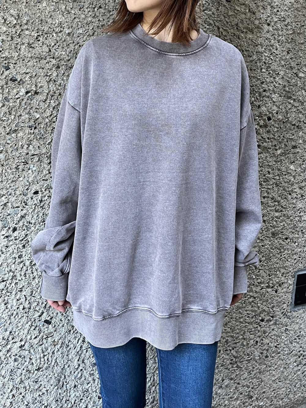 グレー系のスウェット、ブルー系のデニムパンツ、ブラック系のスニーカーを着用したレディースの冬コーディネートの2枚目の写真