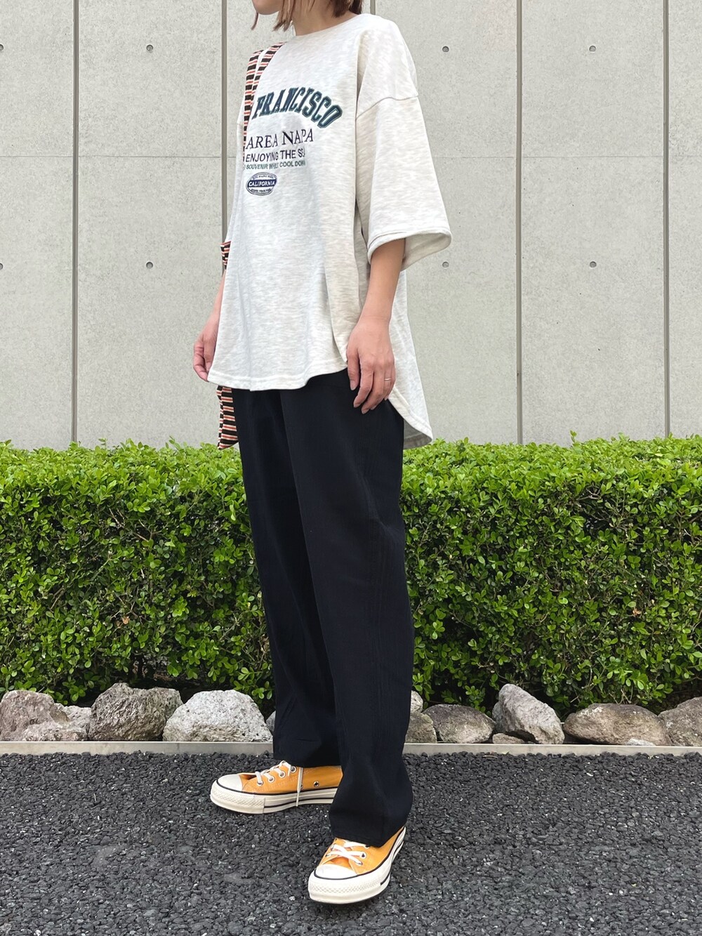 ブラック系のその他パンツ、ホワイト系のTシャツ/カットソー、イエロー系のスニーカーを着用したレディースの春コーディネートの2枚目の写真