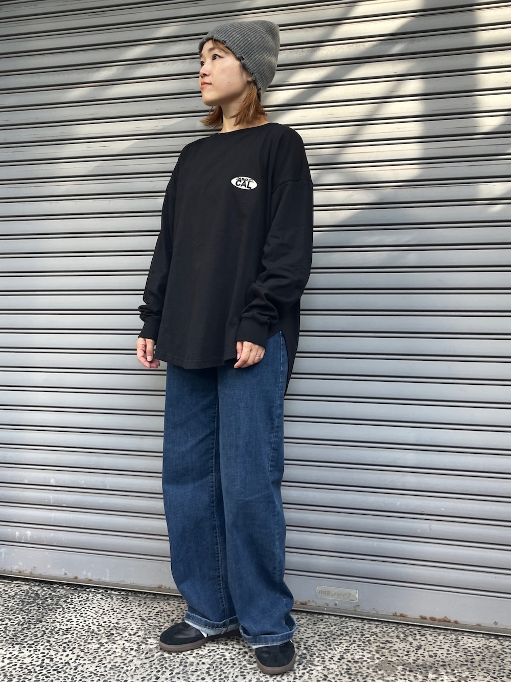 ブラック系のTシャツ/カットソー、ブルー系のデニムパンツ、ブラック系のスニーカーを着用したレディースの秋コーディネートの2枚目の写真