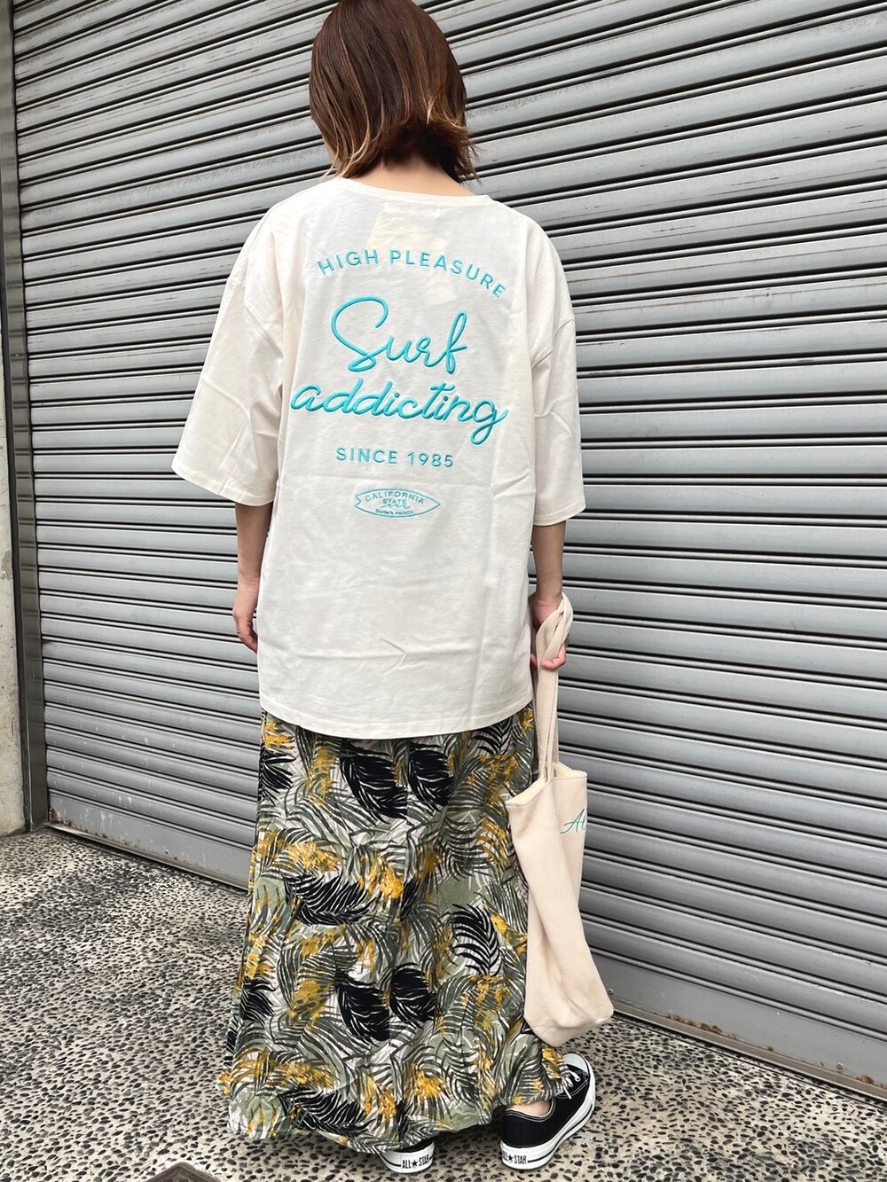 ベージュ系のTシャツ/カットソー、ベージュ系のトートバッグ、グリーン系のスカートを着用したレディースの春コーディネートの2枚目の写真