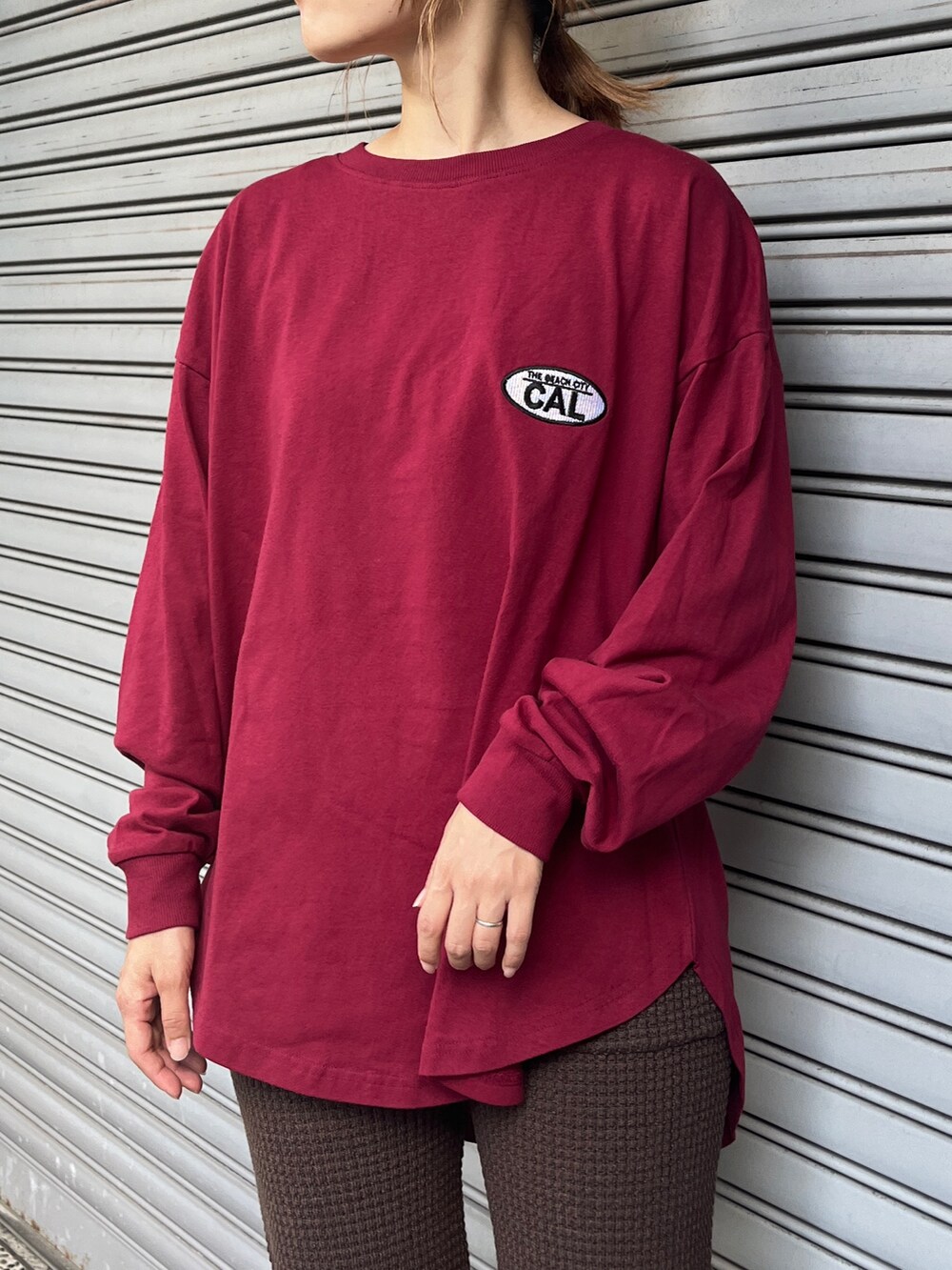 レッド系のTシャツ/カットソー、ブラウン系のその他パンツ、ブラック系のスニーカーを着用したレディースの秋コーディネートの4枚目の写真