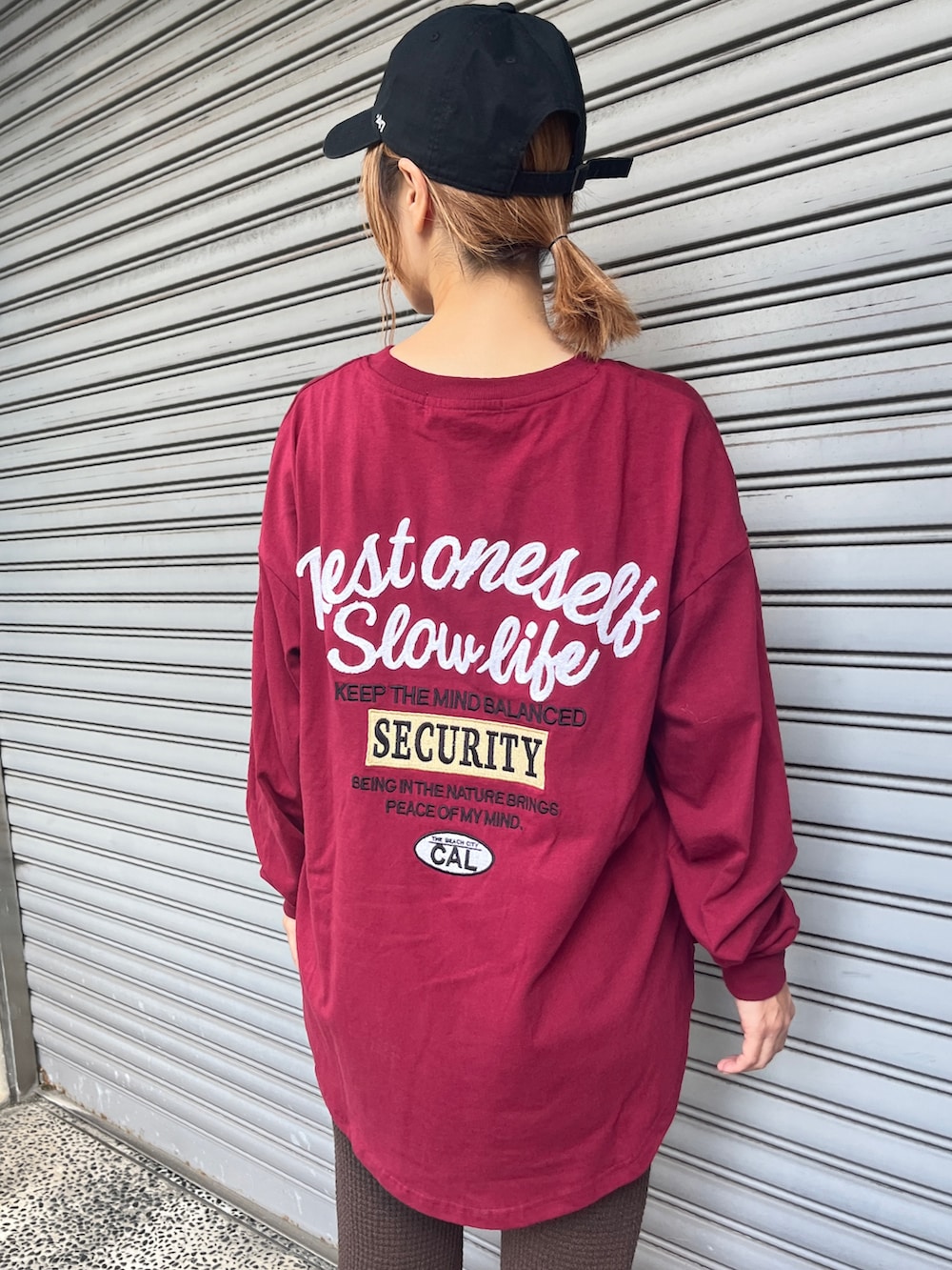 レッド系のTシャツ/カットソー、ブラウン系のその他パンツ、ブラック系のスニーカーを着用したレディースの秋コーディネートの5枚目の写真