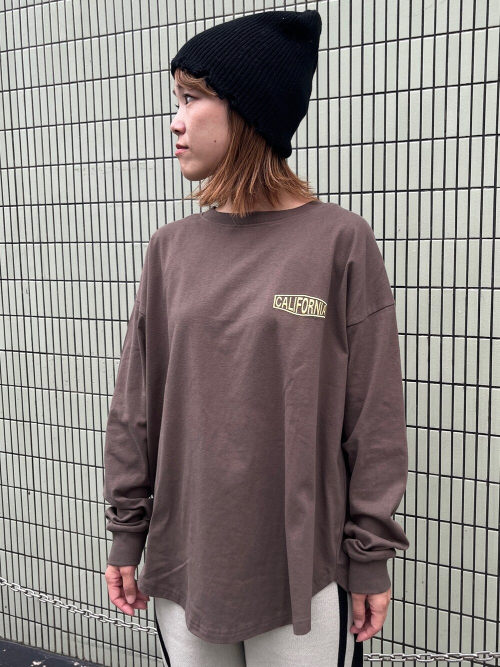 ブラウン系のTシャツ/カットソー、ホワイト系のその他パンツ、ブラック系のスニーカーを着用したレディースの秋コーディネートの2枚目の写真