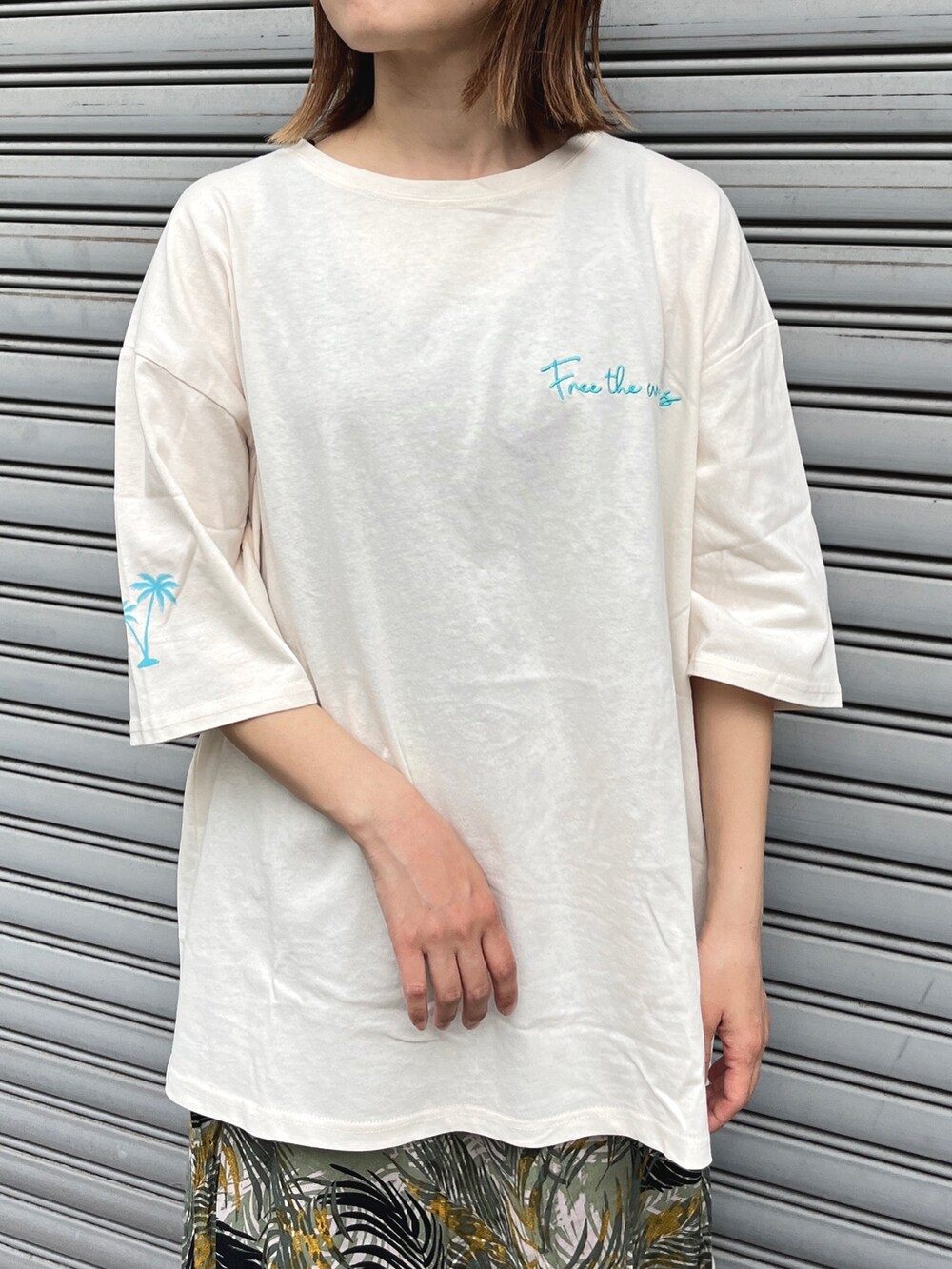 ベージュ系のTシャツ/カットソー、ベージュ系のトートバッグ、グリーン系のスカートを着用したレディースの春コーディネートの3枚目の写真