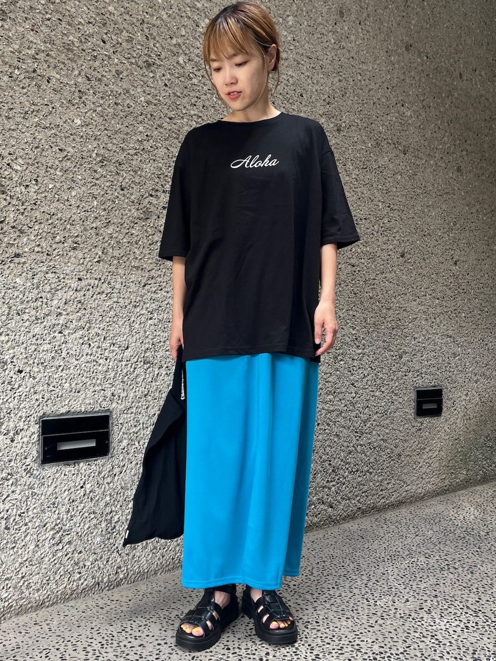 ブラック系のTシャツ/カットソー、ブルー系のスカート、ブラック系のサンダルを着用したレディースの夏コーディネートの2枚目の写真