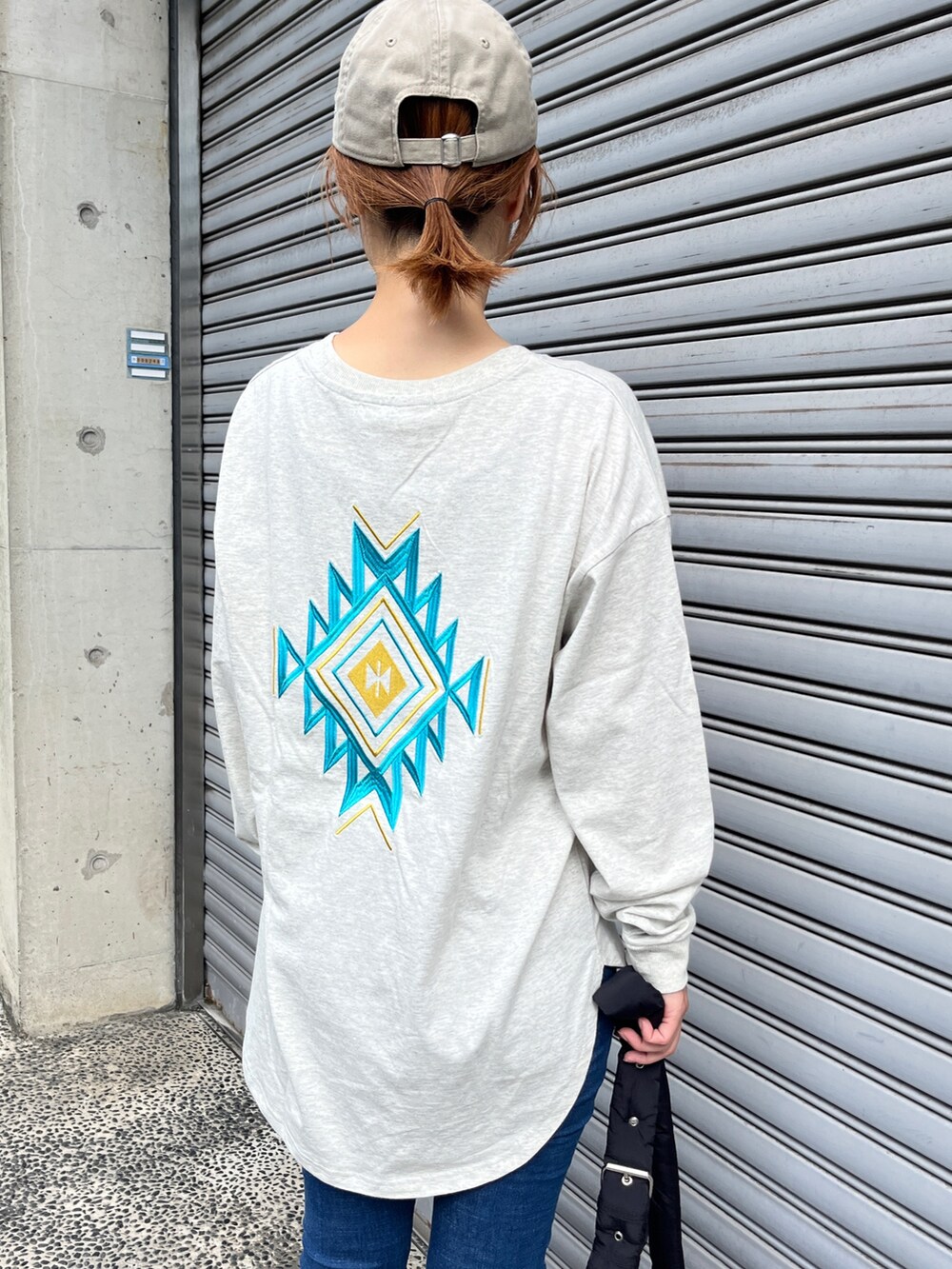 ホワイト系のTシャツ/カットソー、ブルー系のデニムパンツ、ブラック系のスニーカーを着用したレディースの秋コーディネートの4枚目の写真