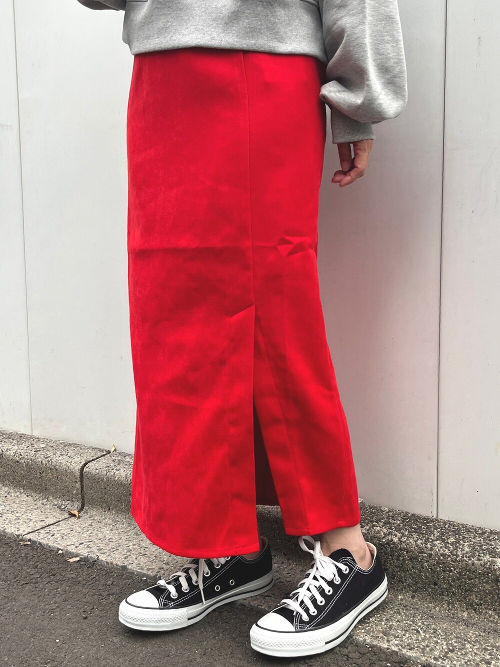 グレー系のスウェット、レッド系のスカート、ブラック系のスニーカーを着用したレディースの秋コーディネートの3枚目の写真