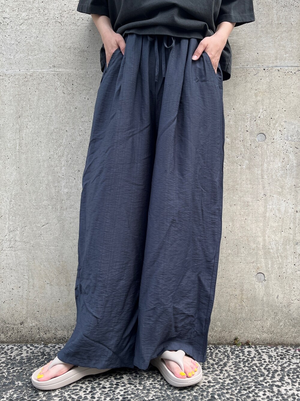 ブラック系のTシャツ/カットソー、ブルー系のその他パンツ、ベージュ系のサンダルを着用したレディースの春コーディネートの3枚目の写真