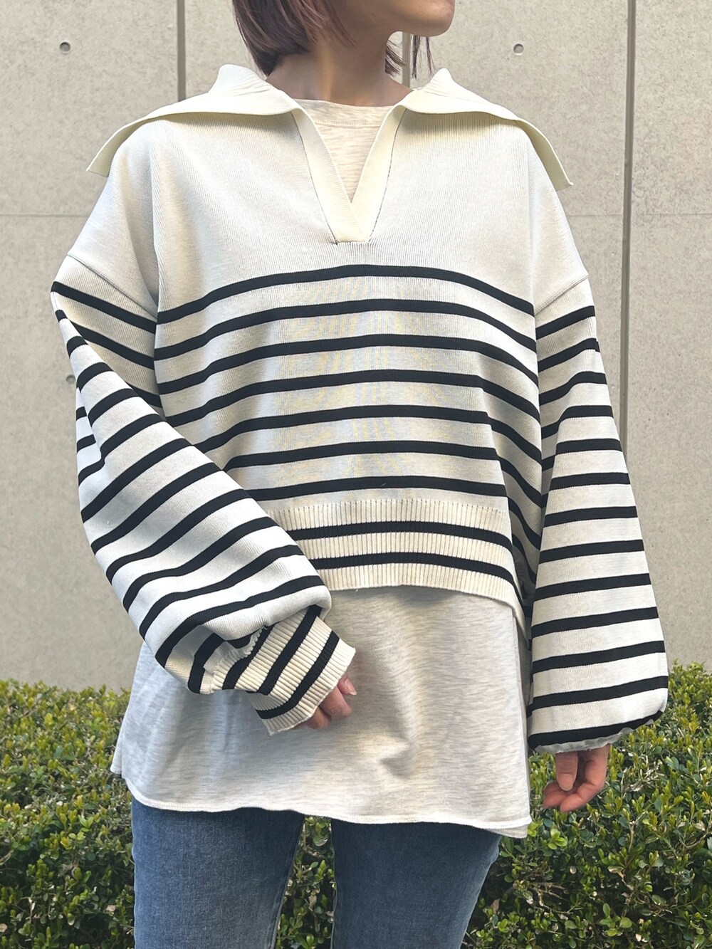 ホワイト系のニット/セーター、ブルー系のデニムパンツを着用したレディースの春コーディネートの2枚目の写真