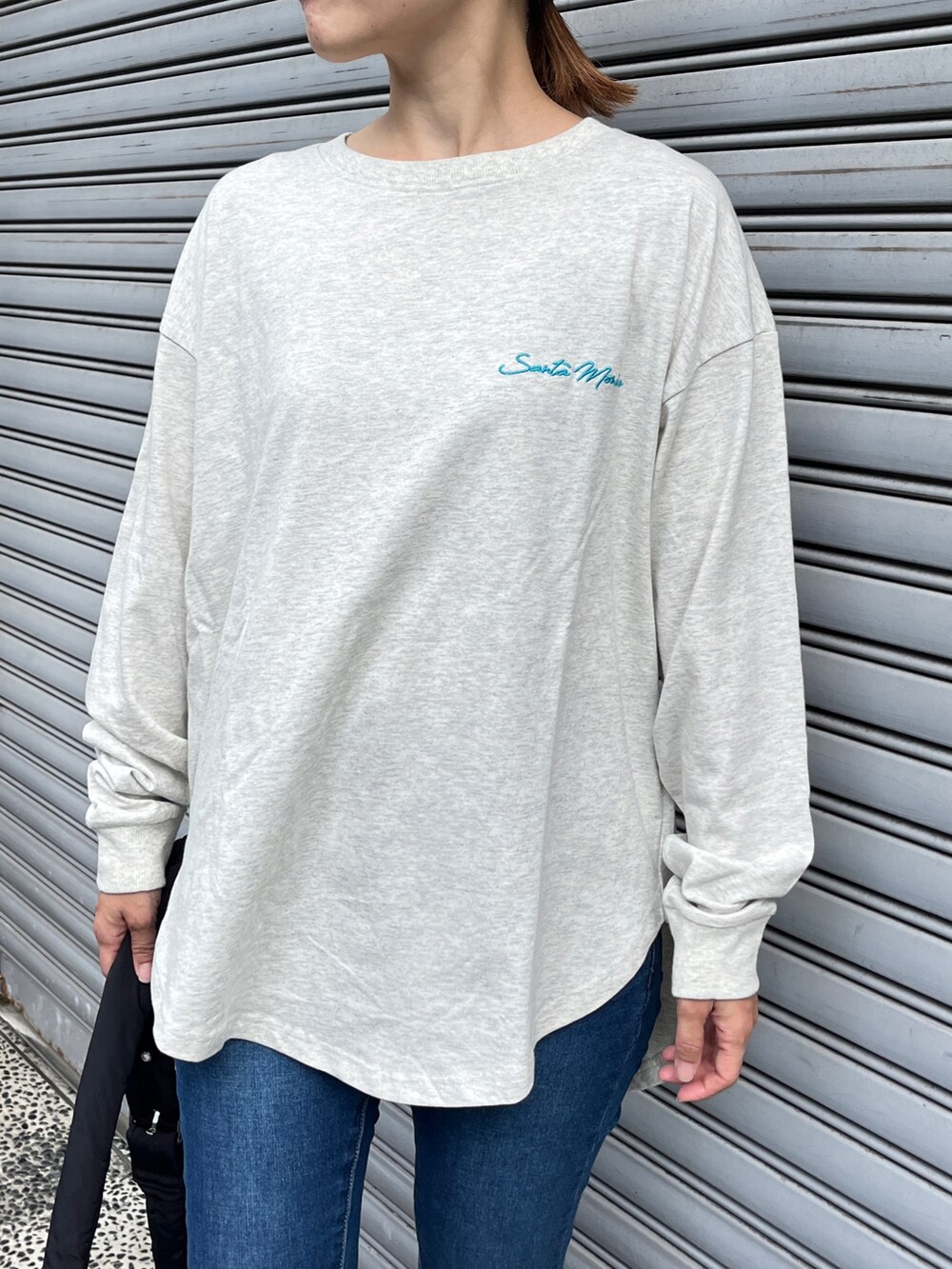 ホワイト系のTシャツ/カットソー、ブルー系のデニムパンツ、ブラック系のスニーカーを着用したレディースの秋コーディネートの3枚目の写真