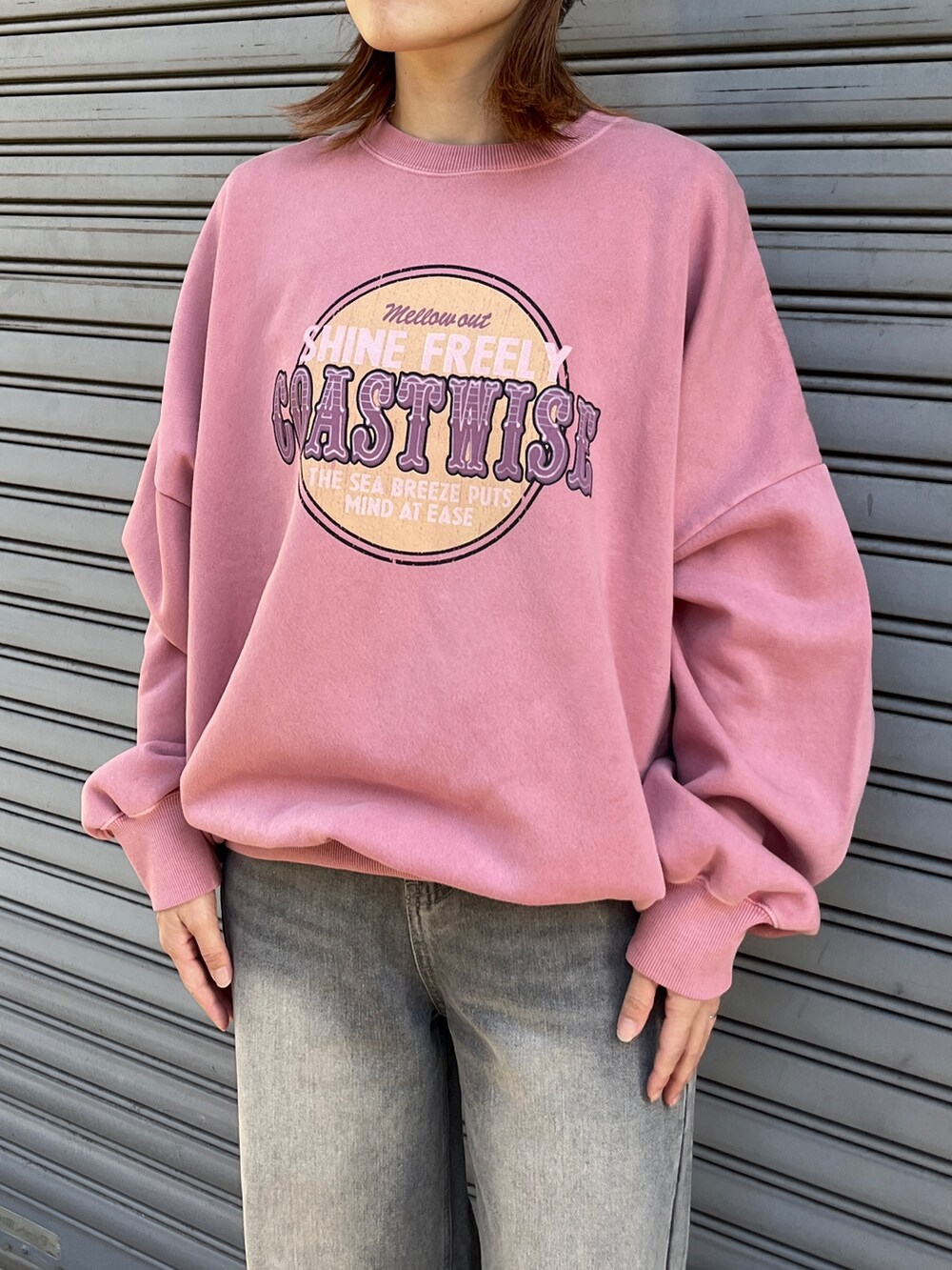 ピンク系のスウェット、ブラック系のデニムパンツ、ブラック系のスニーカーを着用したレディースの冬コーディネートの3枚目の写真