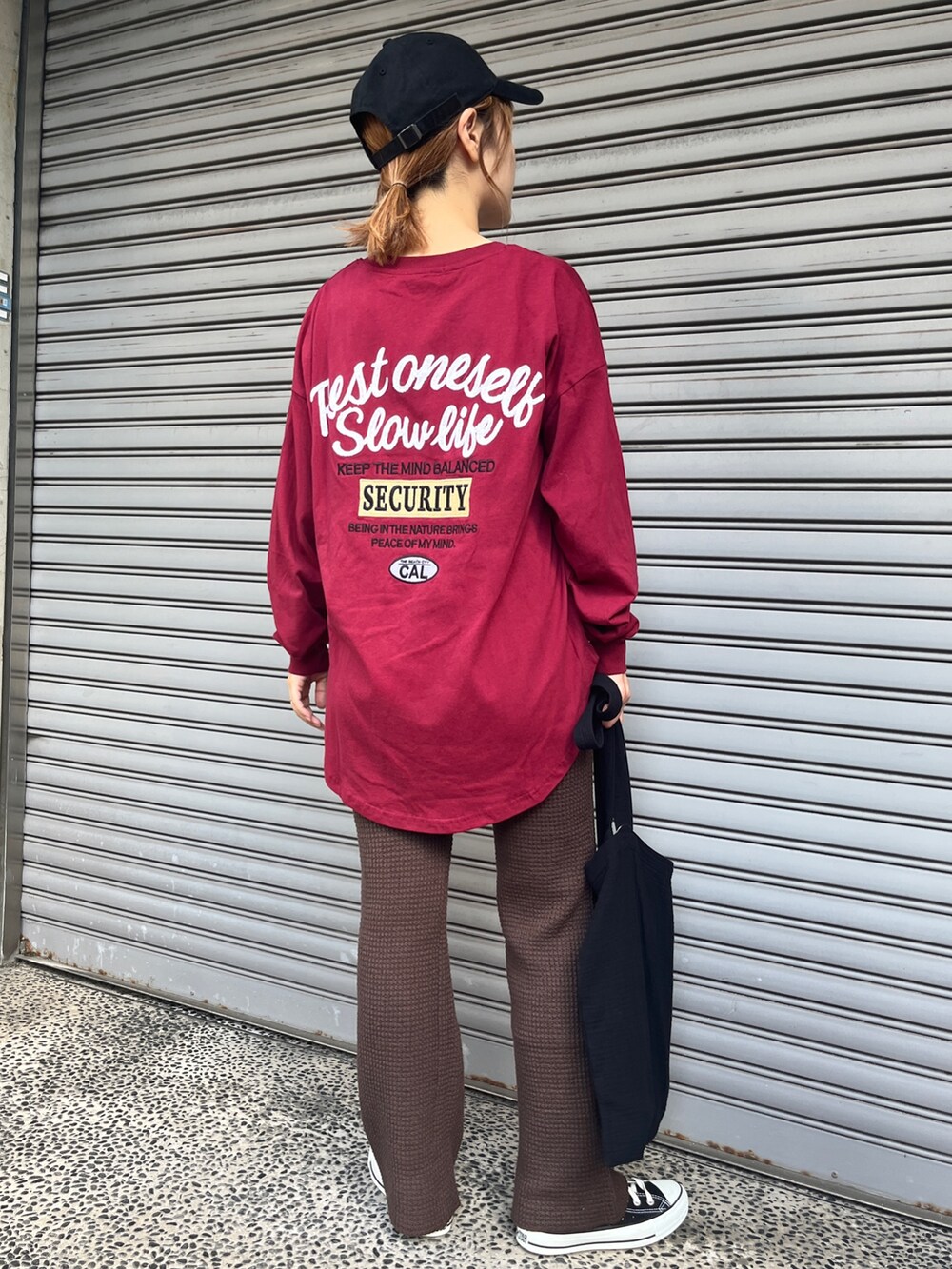 レッド系のTシャツ/カットソー、ブラウン系のその他パンツ、ブラック系のスニーカーを着用したレディースの秋コーディネートの3枚目の写真