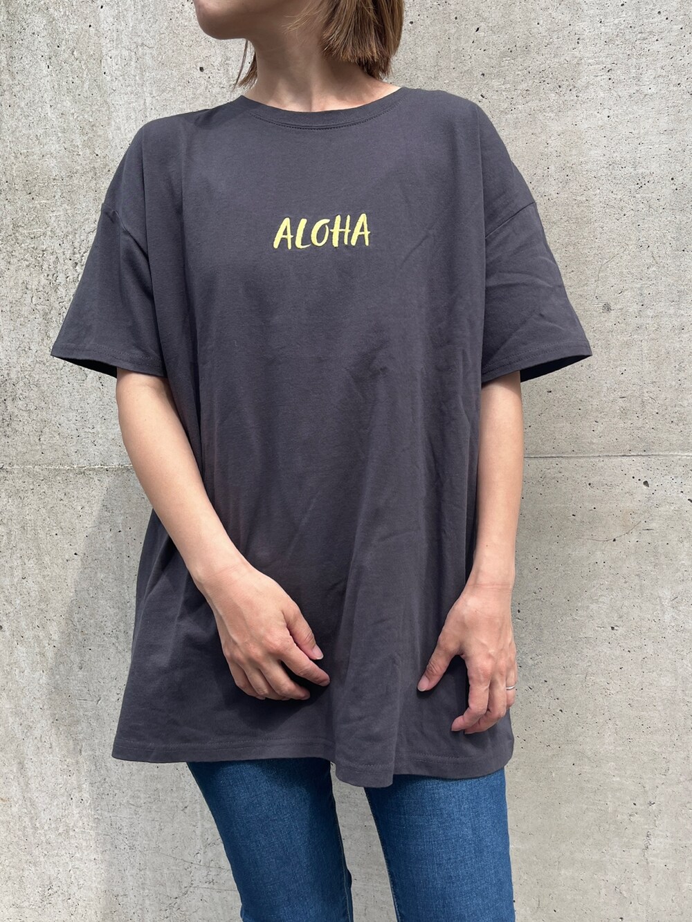 グレー系のTシャツ/カットソー、ブルー系のデニムパンツ、ブラック系のスニーカーを着用したレディースの夏コーディネートの2枚目の写真