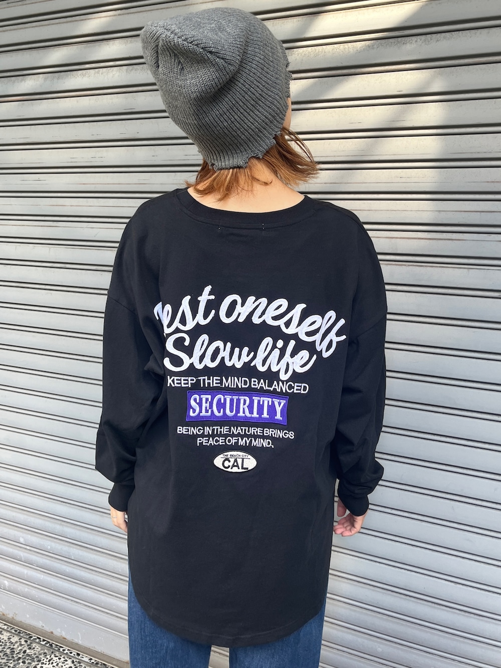 ブラック系のTシャツ/カットソー、ブルー系のデニムパンツ、ブラック系のスニーカーを着用したレディースの秋コーディネートの4枚目の写真