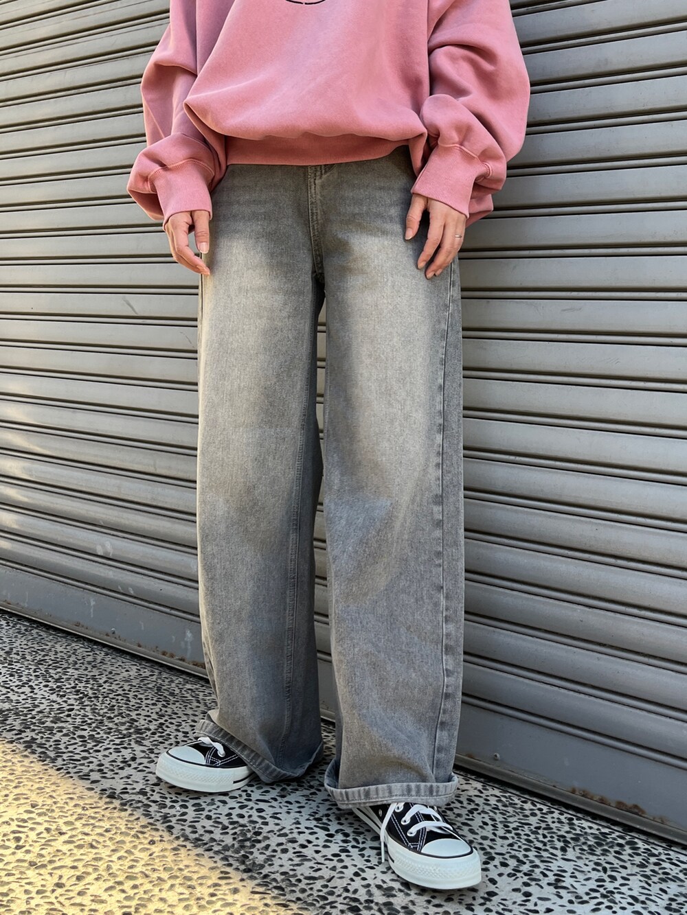 ピンク系のスウェット、ブラック系のデニムパンツ、ブラック系のスニーカーを着用したレディースの冬コーディネートの2枚目の写真