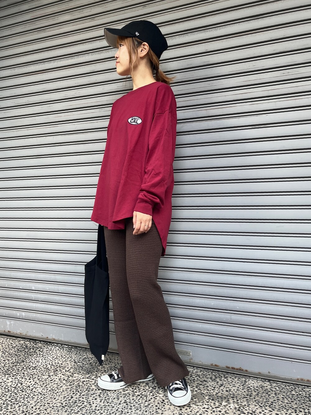 レッド系のTシャツ/カットソー、ブラウン系のその他パンツ、ブラック系のスニーカーを着用したレディースの秋コーディネートの2枚目の写真