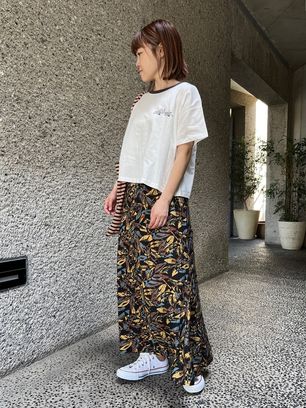 ホワイト系のTシャツ/カットソー、グレー系のスカート、ホワイト系のスニーカーを着用したレディースの春コーディネートの2枚目の写真