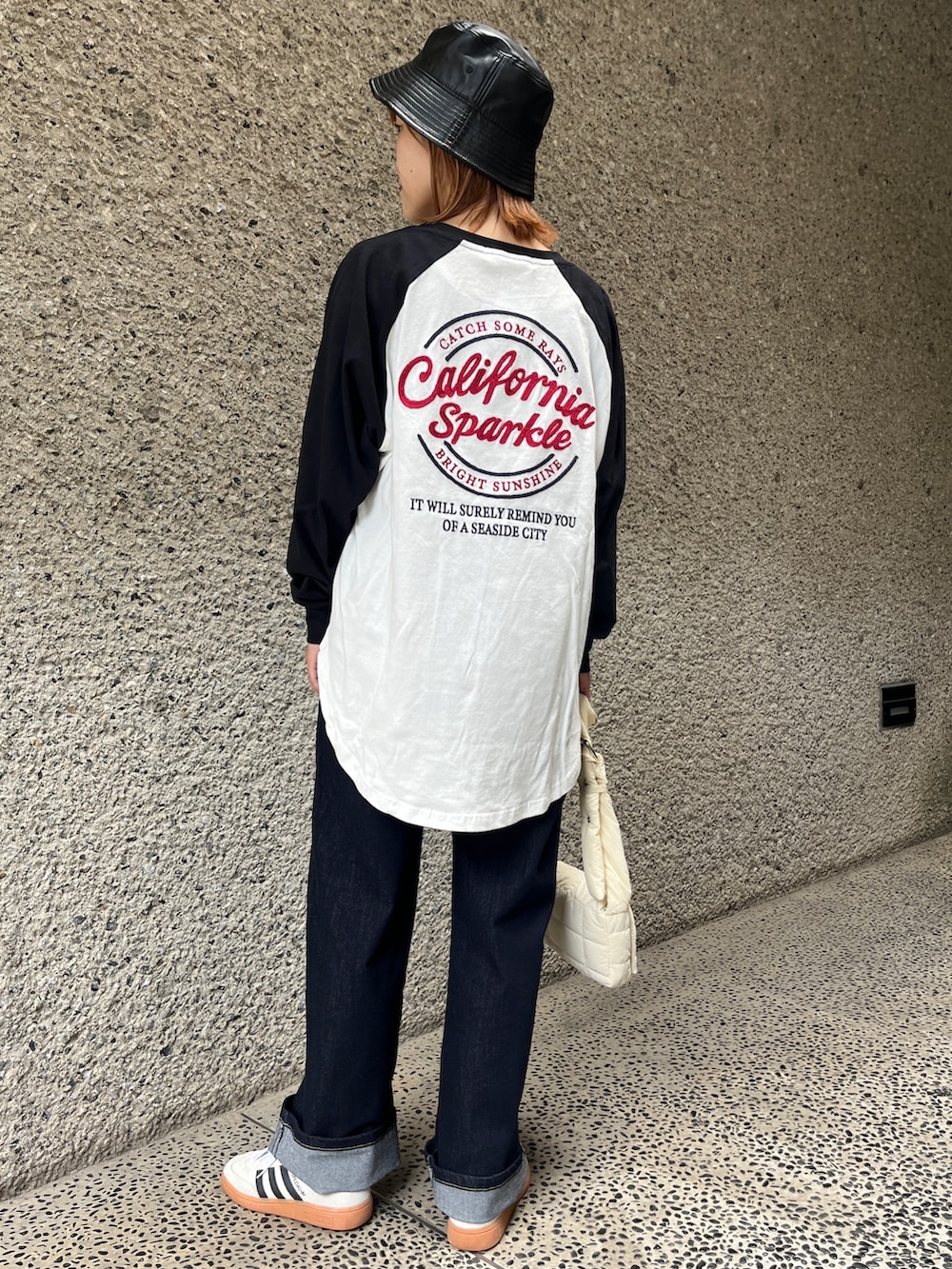 ホワイト系のスニーカー、ホワイト系のショルダーバッグ、ブルー系のデニムパンツを着用したレディースの秋コーディネートの2枚目の写真