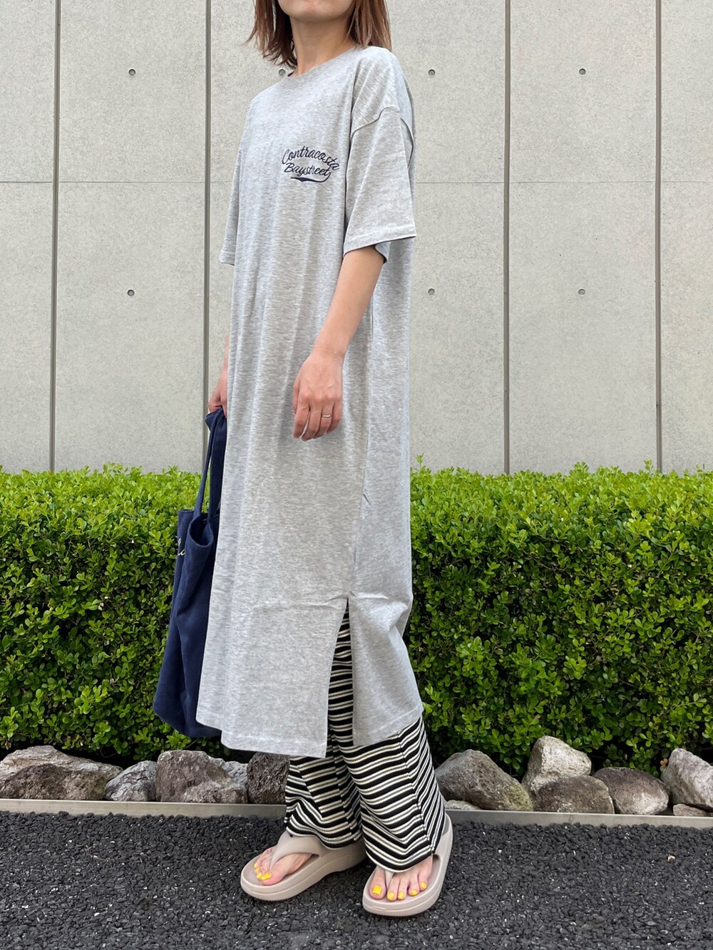 グレー系のワンピース、ブルー系のトートバッグ、ベージュ系のサンダルを着用したレディースの夏コーディネートの3枚目の写真