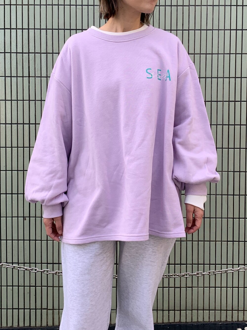 パープル系のスウェット、グレー系のスウェットパンツ、ホワイト系のバッグを着用したレディースの冬コーディネートの4枚目の写真