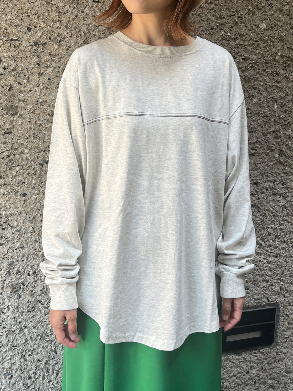 グリーン系のスカート、ホワイト系のショルダーバッグ、ブラック系のスニーカーを着用したレディースの秋コーディネートの2枚目の写真