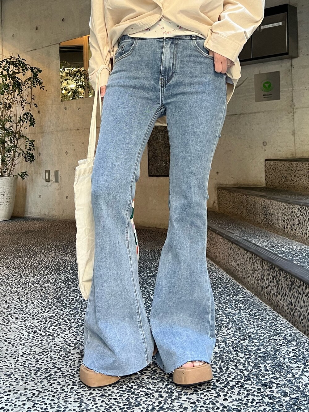 ベージュ系のシャツ/ブラウス、ホワイト系のTシャツ/カットソー、ブルー系のデニムパンツを着用したレディースの春コーディネートの5枚目の写真