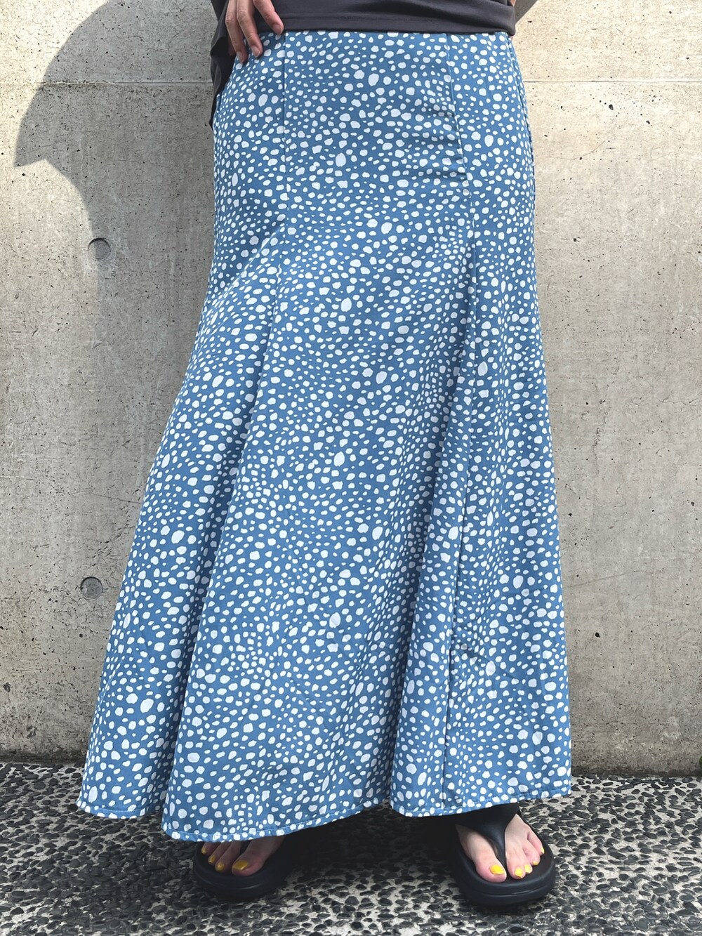 グレー系のTシャツ/カットソー、ブルー系のスカート、ブラック系のサンダルを着用したレディースの夏コーディネートの5枚目の写真