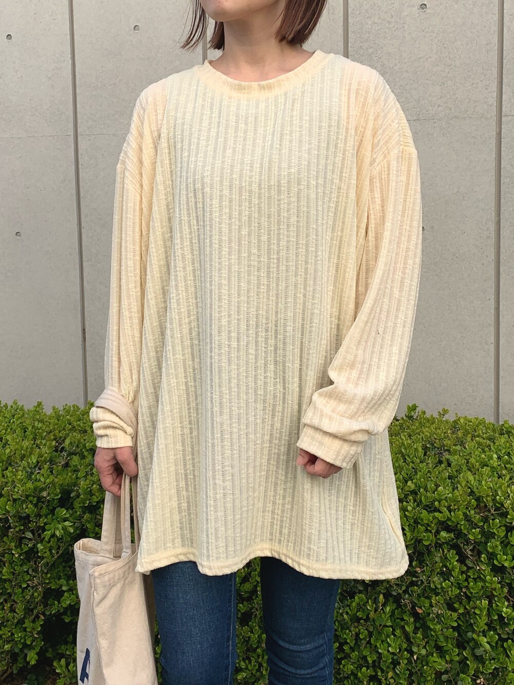 イエロー系のワンピース、ブルー系のデニムパンツ、ホワイト系のスニーカーを着用したレディースの春コーディネートの2枚目の写真