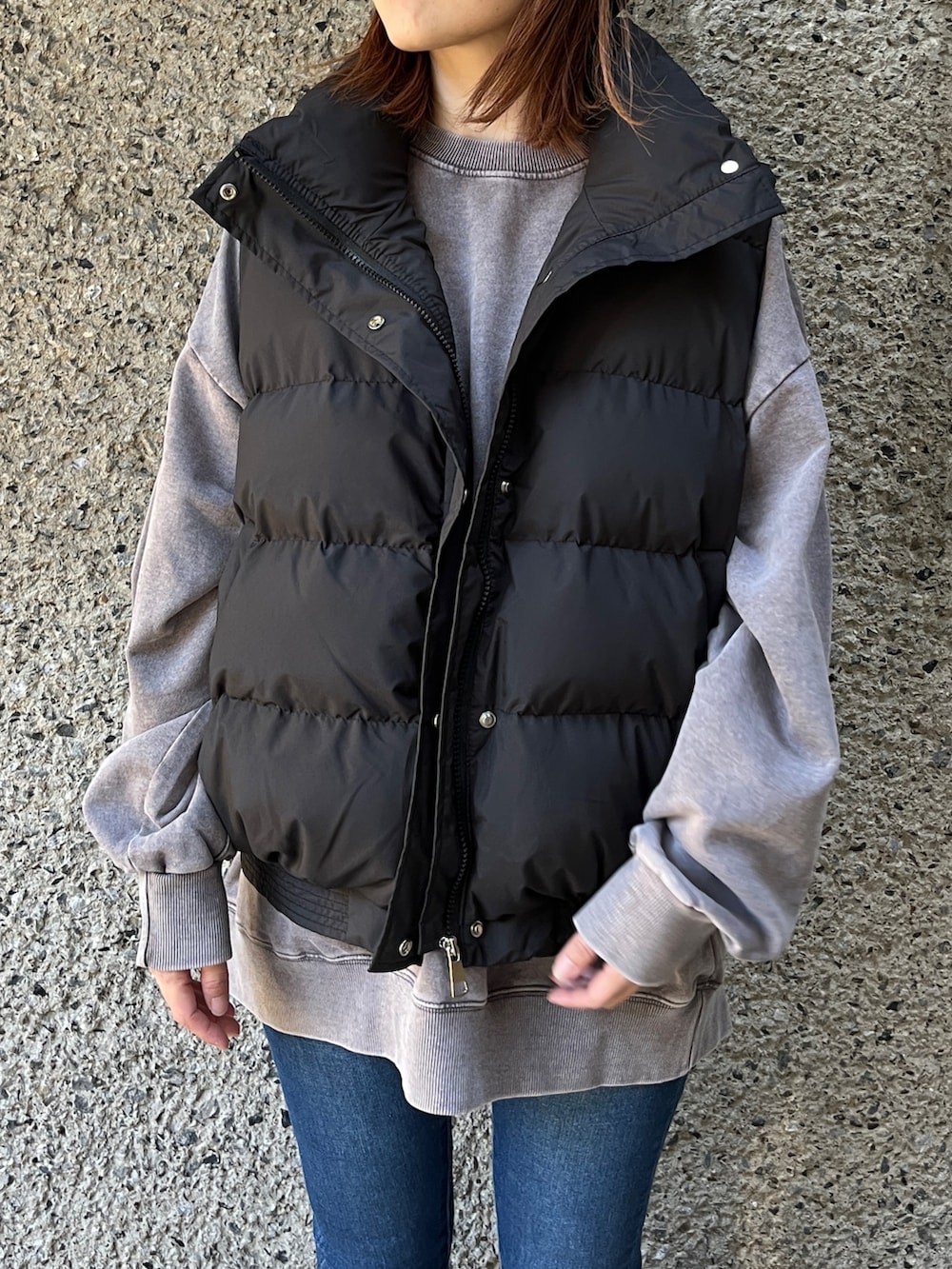 ブラック系のダウンベスト、ブルー系のデニムパンツ、ブラック系のスニーカーを着用したレディースの冬コーディネートの2枚目の写真