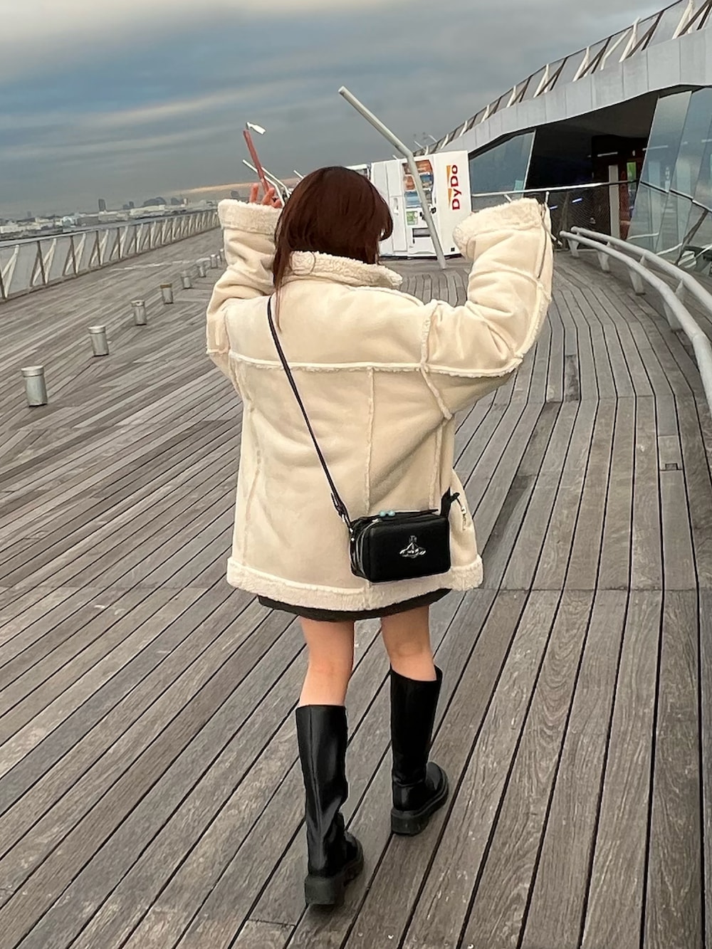 ブラック系のブーツ、ホワイト系のムートンコート、ブラック系のスカートを着用したレディースの冬コーディネートの3枚目の写真