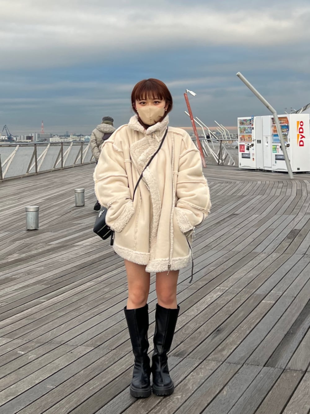 ブラック系のブーツ、ホワイト系のムートンコート、ブラック系のスカートを着用したレディースの冬コーディネートの2枚目の写真