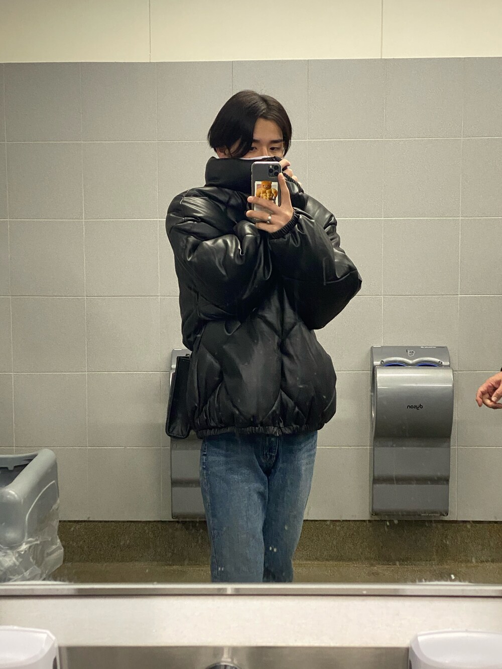 ブラック系のダウンベスト、ブルー系のデニムパンツ、ブラック系のスニーカーを着用したメンズの冬コーディネートの2枚目の写真