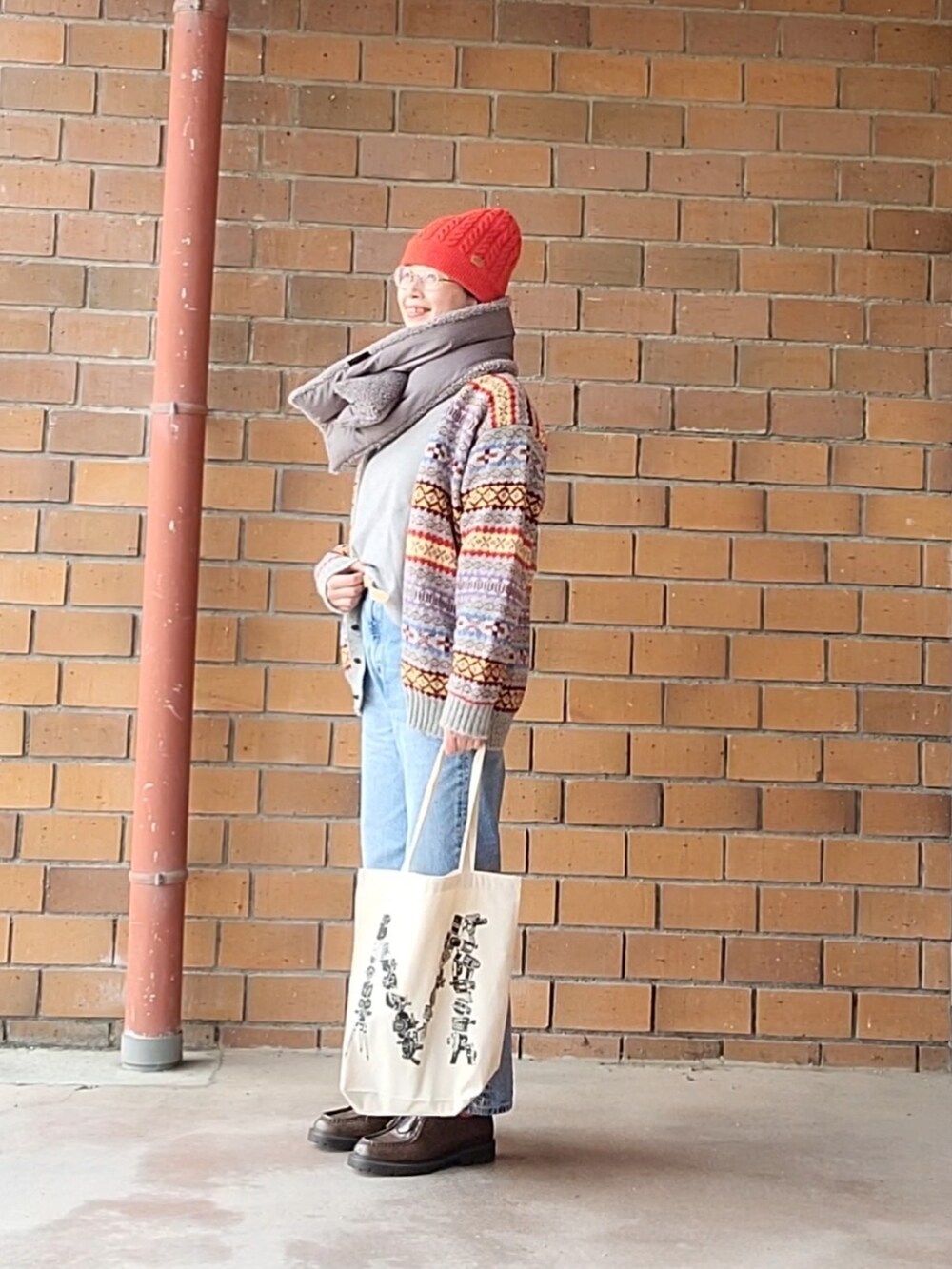 グレー系のカーディガン/ボレロ、ブルー系のデニムパンツ、ホワイト系のトートバッグを着用したレディースの冬コーディネートの2枚目の写真