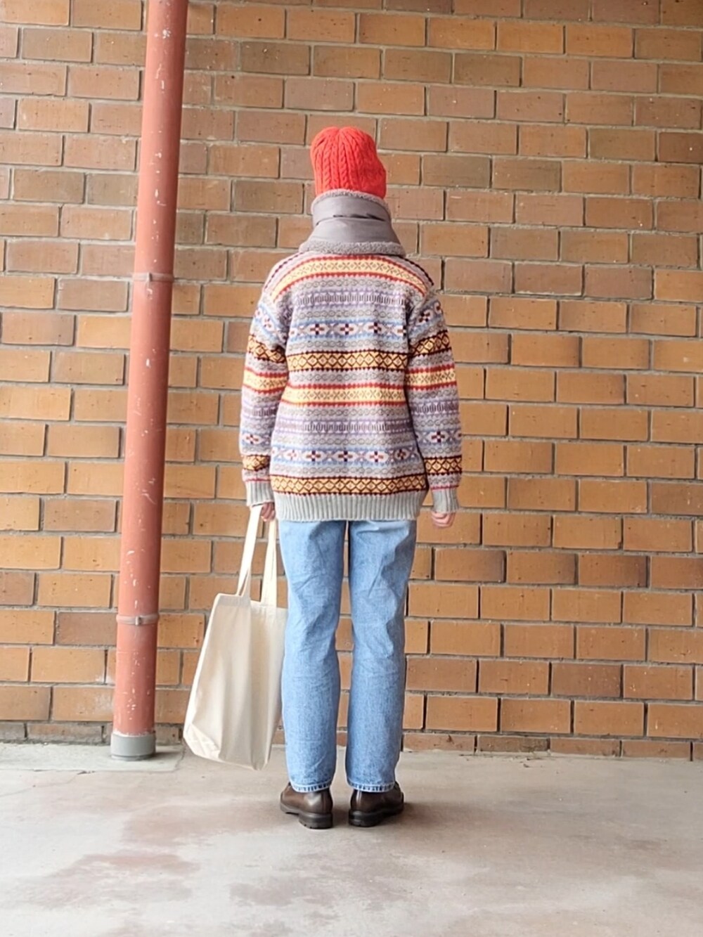 グレー系のカーディガン/ボレロ、ブルー系のデニムパンツ、ホワイト系のトートバッグを着用したレディースの冬コーディネートの3枚目の写真