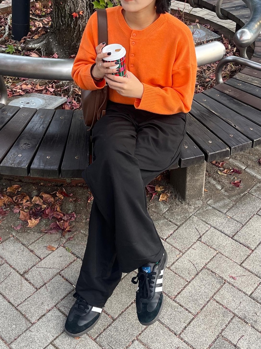 オレンジ系のニット/セーター、ブラック系のスニーカーを着用したレディースの秋コーディネートの2枚目の写真