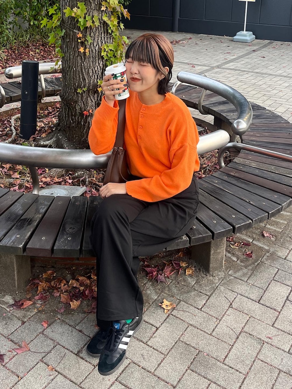 オレンジ系のニット/セーター、ブラック系のスニーカーを着用したレディースの秋コーディネートの5枚目の写真