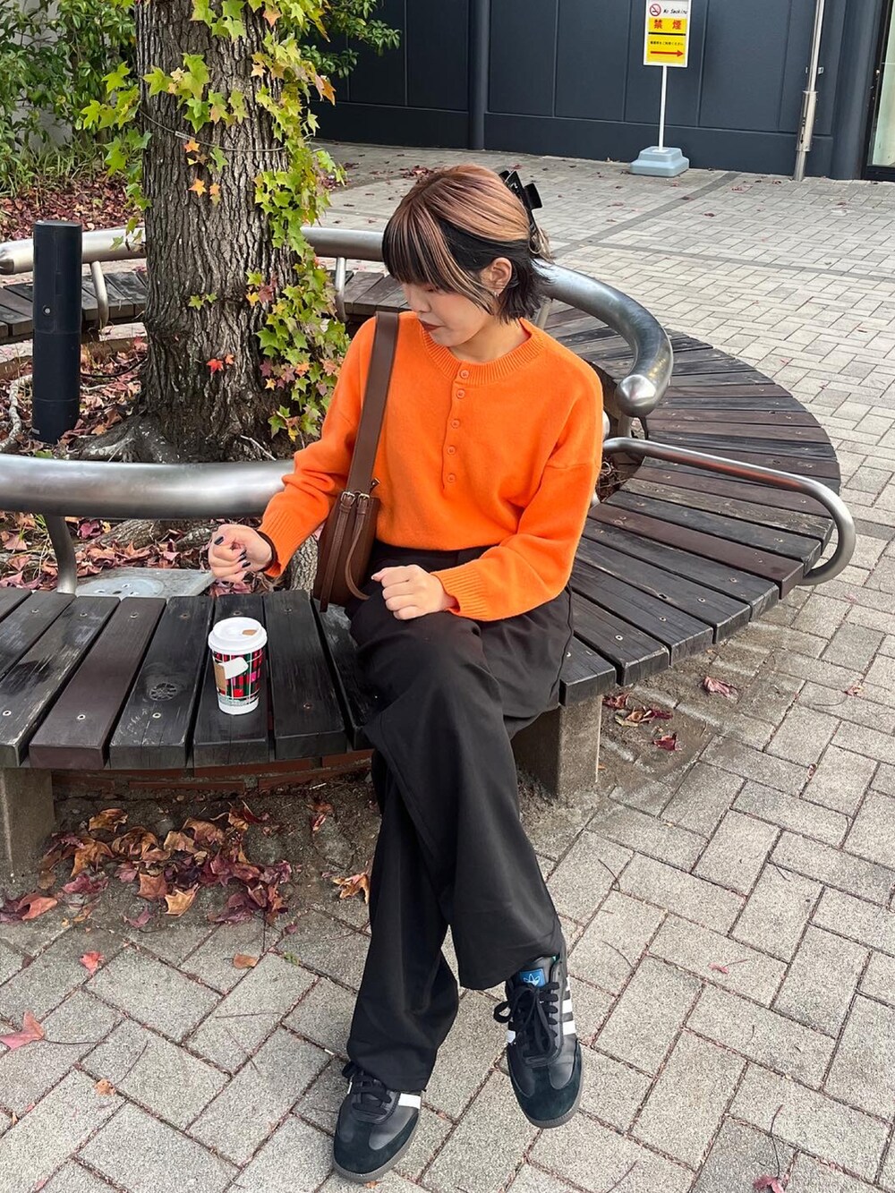 オレンジ系のニット/セーター、ブラック系のスニーカーを着用したレディースの秋コーディネートの3枚目の写真