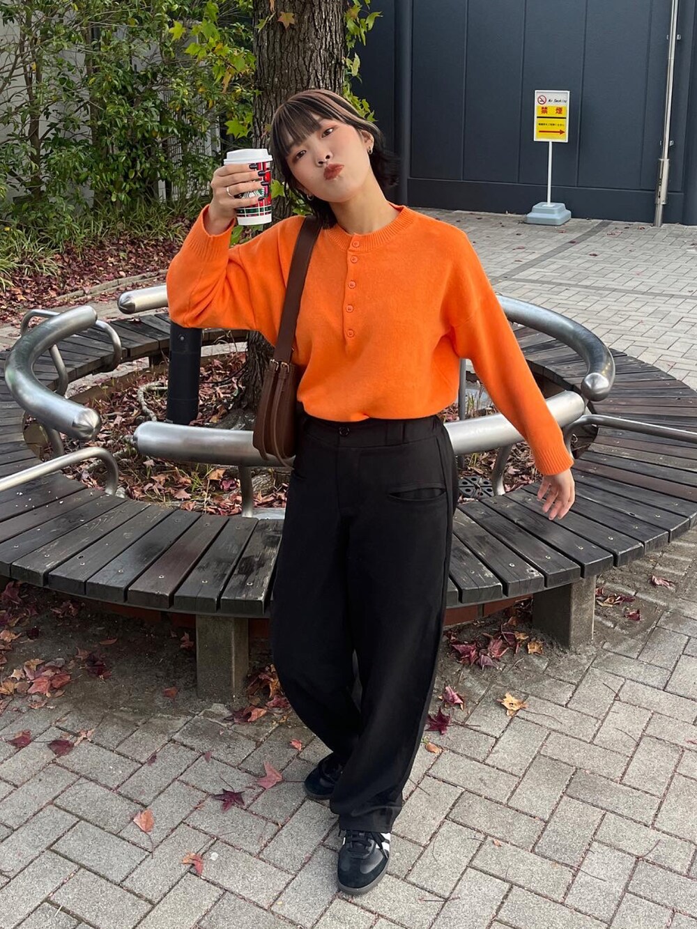 オレンジ系のニット/セーター、ブラック系のスニーカーを着用したレディースの秋コーディネートの4枚目の写真