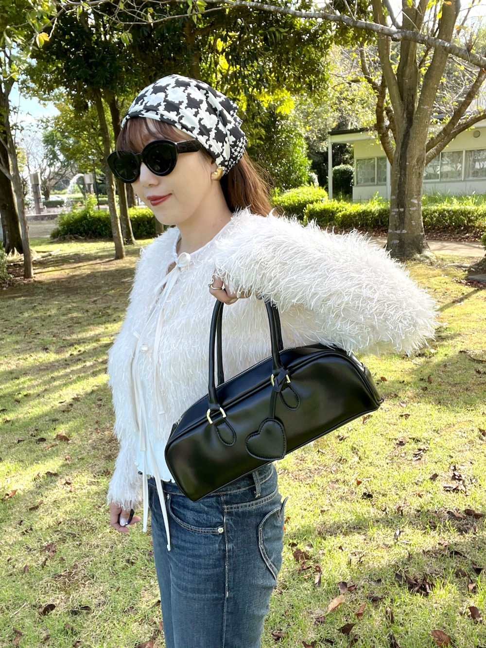 ブラック系のボストンバッグ、ホワイト系のカーディガン/ボレロ、ブルー系のデニムパンツを着用したレディースの秋コーディネートの5枚目の写真