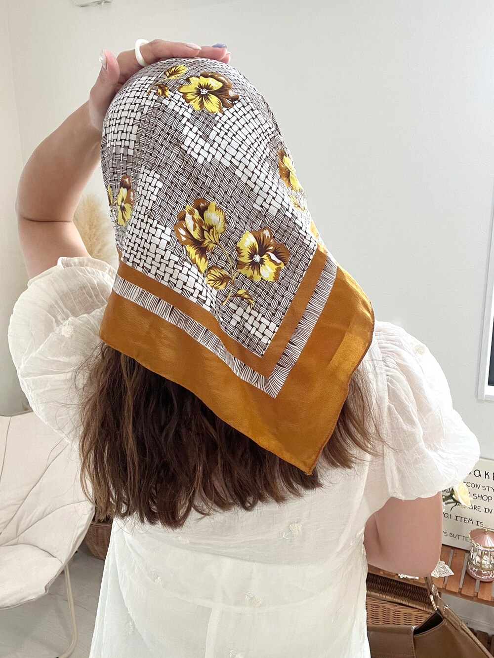 ブラウン系のハンドバッグ、ホワイト系のワンピースを着用したレディースの秋コーディネートの3枚目の写真