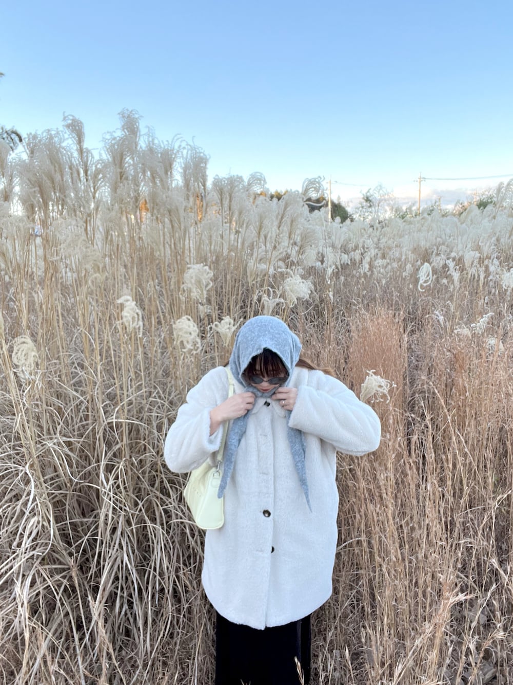 イエロー系のショルダーバッグ、ベージュ系のステンカラーコートを着用したレディースの冬コーディネートの2枚目の写真