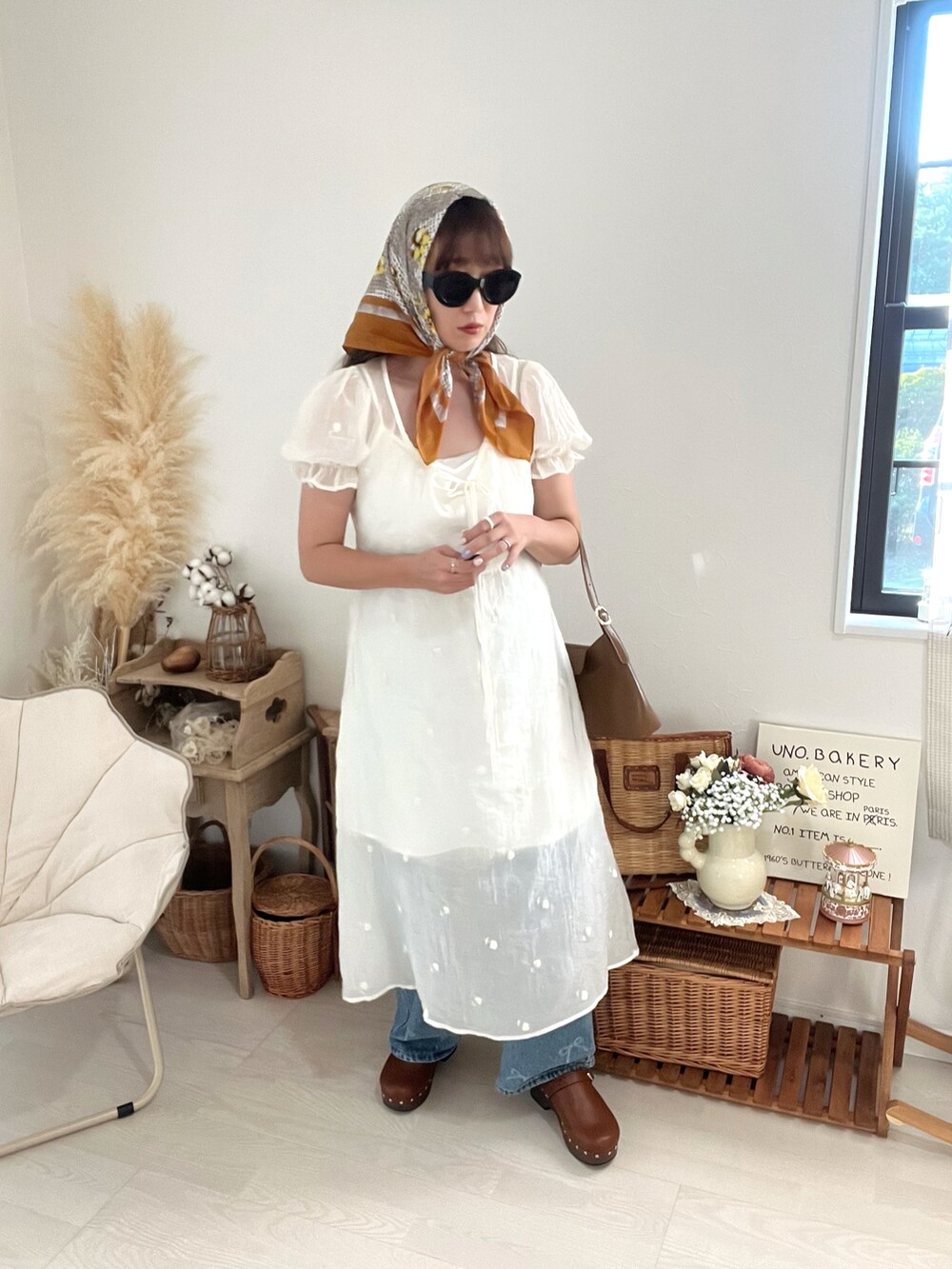 ブラウン系のハンドバッグ、ホワイト系のワンピースを着用したレディースの秋コーディネートの5枚目の写真